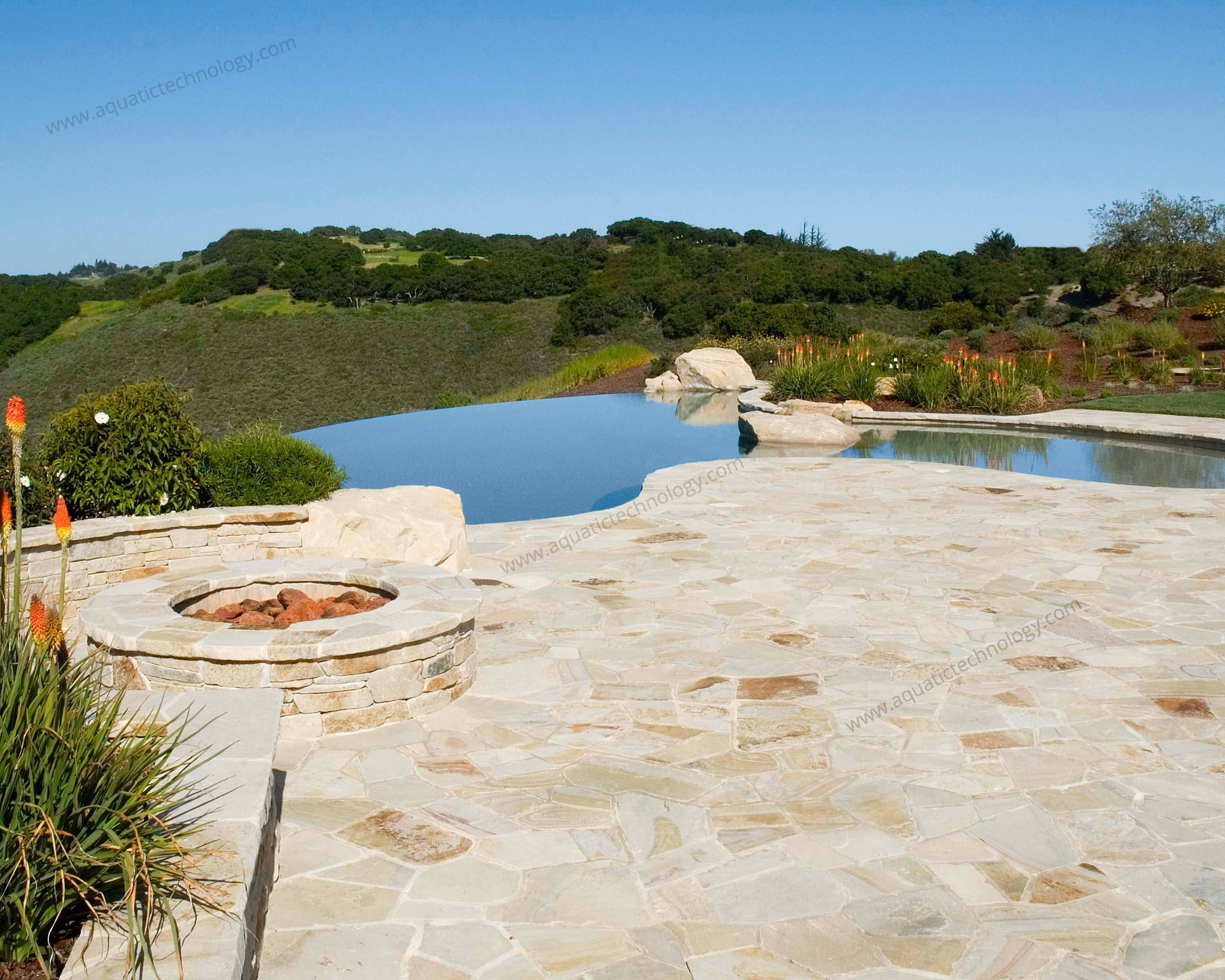 Infinity edge pool stone patio gas fire feature